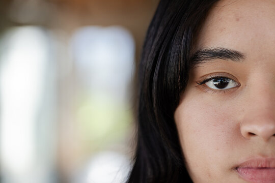 African American woman gazing toward camera, showing right face inside building with window light