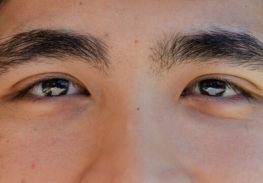 African American man gazing outdoors, showing close-up eyes with reflections, eyebrows, mole, pores