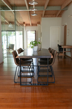 Solid-wood table with metal legs sitting on hardwood floors, eight leather chairs flanking
