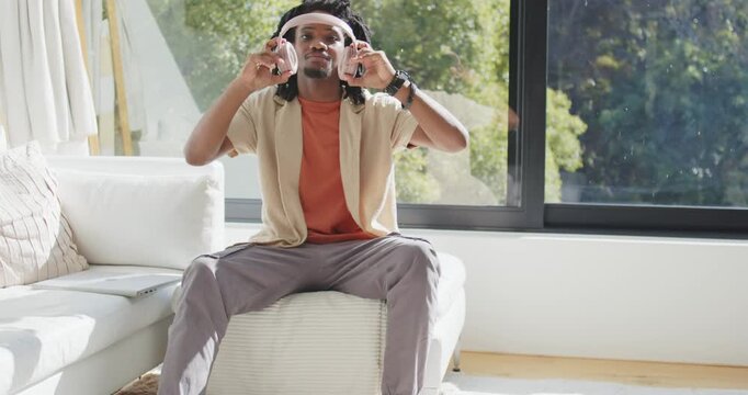 Adult man at home preparing to listen, lifting rose headset, adjusting then gazing out window