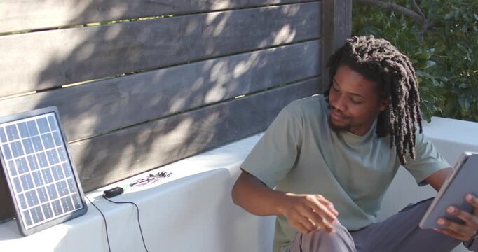 Man sitting on bench, noticing solar panel, aligning plug, preparing tablet charging, copy space