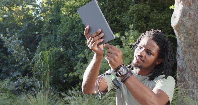 African American man inspecting tip, aligning green cable and inserting plug into tablet outdoors