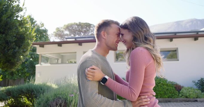 Couple standing outside house, facing, leaning in, embracing, expressing love, smartwatch visible