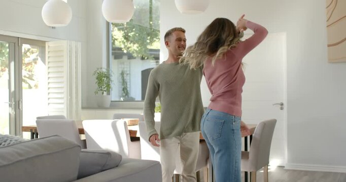 Couple man offering hand, woman accepting and twirling, embracing near dining table, sharing love