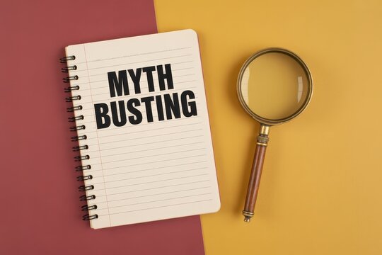 MYTH BUSTING text written on notebook with magnifying glass on a dual-tone background