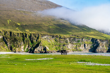 Obraz premium Southern Keel Beach on Achill Island, County Mayo, Ireland, with a pebble shore beneath dramatic sea cliffs. This image shows the rugged coastal edge of the beach from ground level.