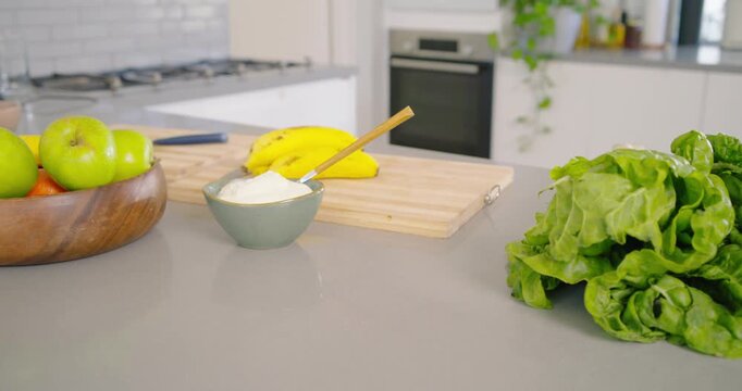 Camera is panning left across kitchen countertop to shift focus onto wooden bowl of green apples