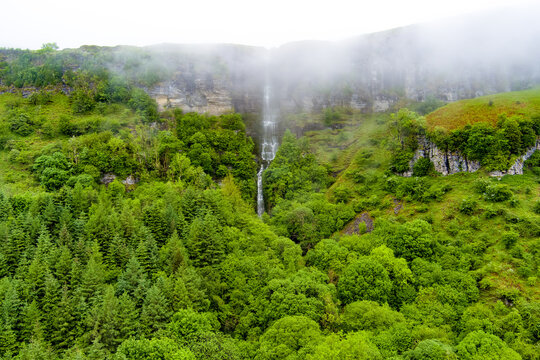 Devils Chimney Waterfall dropping through misty cliffs near Glencar Lough, Ireland. Dramatic cascade in the lush northwest landscape of County Sligo and Leitrim.
