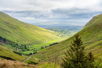Obraz premium Glengesh Pass winding through a green mountain valley in County Donegal, Ireland. A scenic road landscape of the Wild Atlantic Way and remote Irish highlands.