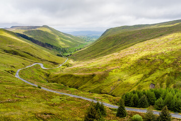 Obraz premium Aerial view of Glengesh Pass curving through a broad green valley in County Donegal, Ireland. A dramatic birds eye landscape of remote mountains and winding roads