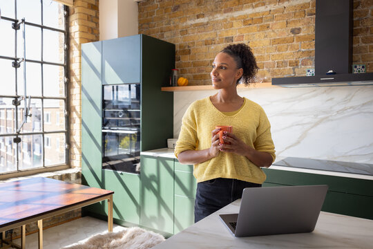 Woman Contemplating home finances using a laptop in her kitchen