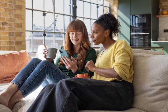 Two Women Smiling While Viewing Phone Content