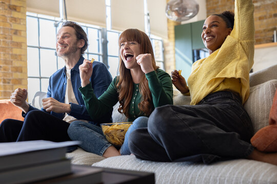 Friends cheering whilst watching sports on TV
