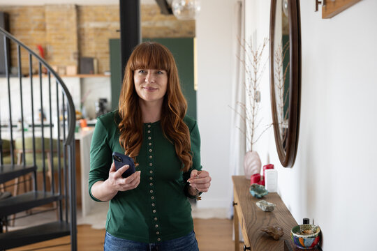 Woman on her way out of the house holding her phone and keys
