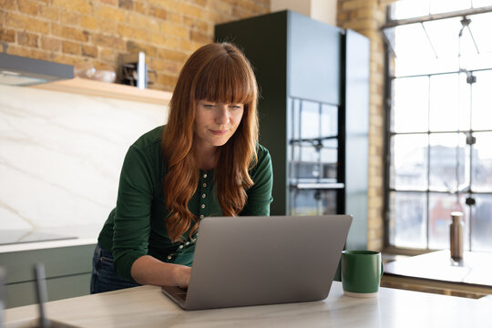 Woman intensely focused on laptop in trendy kitchen