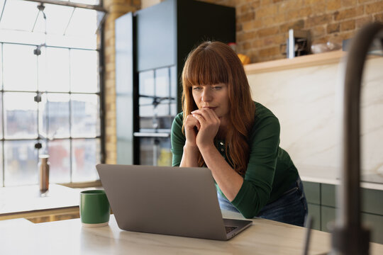 Woman Working on Laptop in Cozy Kitchen Setting