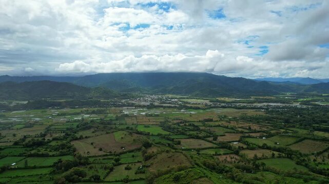 Aerial drone footage of the valley in Poto Tano nearby Mantar hill paragliding point of start, in West Sumabawa, Indonesia, in a cloudy atmosphere, with fields of crops, and villages around