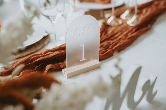 Num&eacute;ro de table sur un chemin de table terracotta, d&eacute;coration de mariage