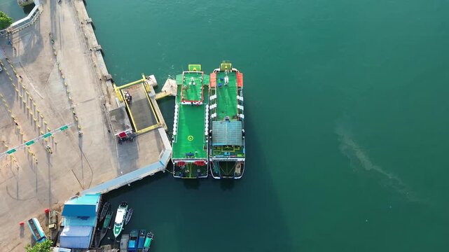 Aerial drone perspective capturing vibrant green ferries docked at a busy maritime terminal