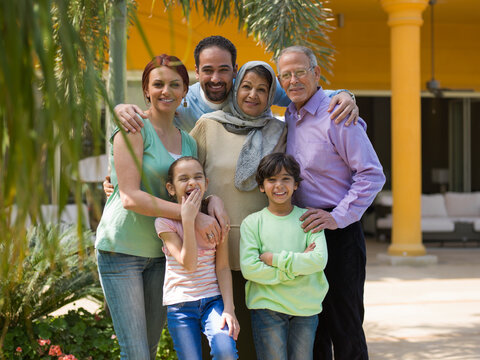 Middle Eastern multigeneration family smiling together at a modern luxury villa courtyard