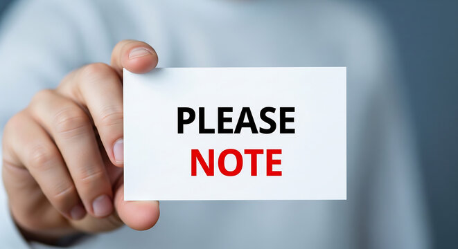 Professional hand holding a white note card with bold red text reading please note for urgent business communication or important meeting reminders in a clean office setting with soft natural lighting