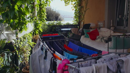 Obraz premium Laundry Hanging on Terrace with Plants Furniture and Distant Lake View Creating Peaceful Domestic Scene of Fresh Air Routine and Outdoor Home Living