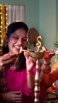 Two happy Indian couples share bright smiles and bonding moments while lighting samai with diyas celebrate Diwali in joyful spirit