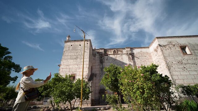 Mature woman enjoys her sightseeing time at the Mission Church located in San Ignacio Baja California surrounded by beautiful scenery