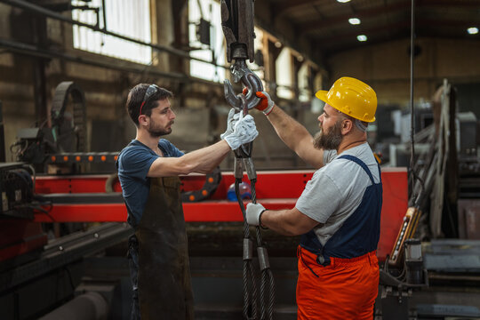 Industrial workers preparing heavy lifting equipment in factory
