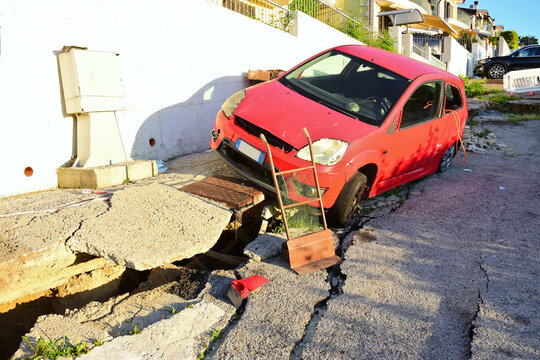 auto rossa che precipita in strada spaccata dopo una frana incidente automobilistico