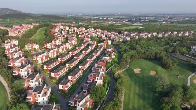 Aerial view of red-roofed townhouse clusters beside a well-maintained golf course in a suburban residential community