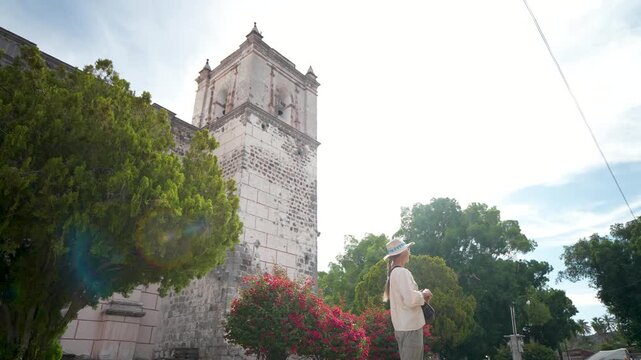 A mature woman explores the Mission Church in San Ignacio, Baja California, Mexico while taking in the sights and enjoying the weather.