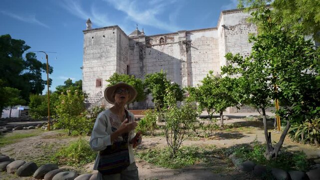 A mature woman visits Mission Church in San Ignacio, Baja California Sur, Mexico, taking in the sights and enjoying the outdoor space.