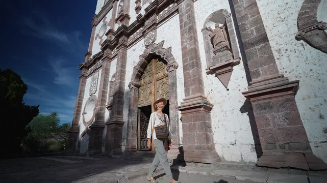 Mature woman walks around Mission Church in San Ignacio, Baja California, Mexico enjoying her time as a tourist in the area.