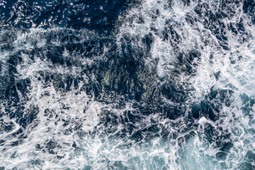 Fototapeta premium Ocean wave with white foam and dark blue water, top view sea texture 
