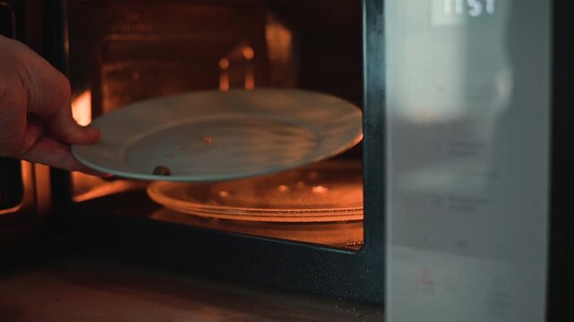 A close-up of a person examining an empty plate with crumbs in a microwave