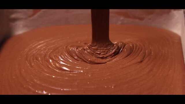 Pouring chocolate cake batter with the help of electric blender in a glass bowl