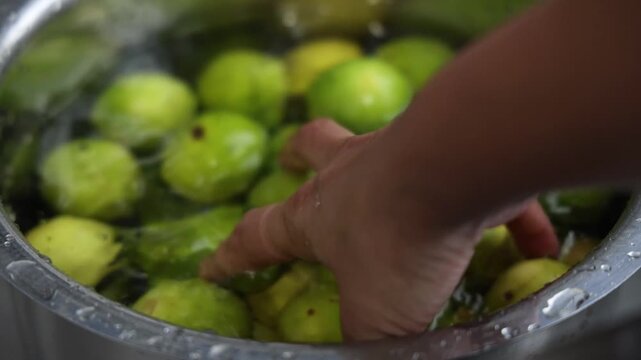 Hands cleaning a vessel full of a nimbu, lemon
