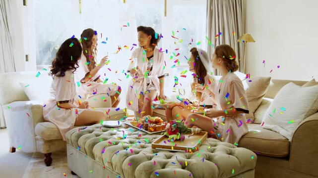 Four women reacting to confetti burst, raising phone and toasting in living room for social media