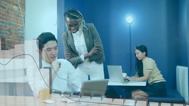 Female leaning in pointing while male tapping laptop, reviewing sales data with bar-line graphs