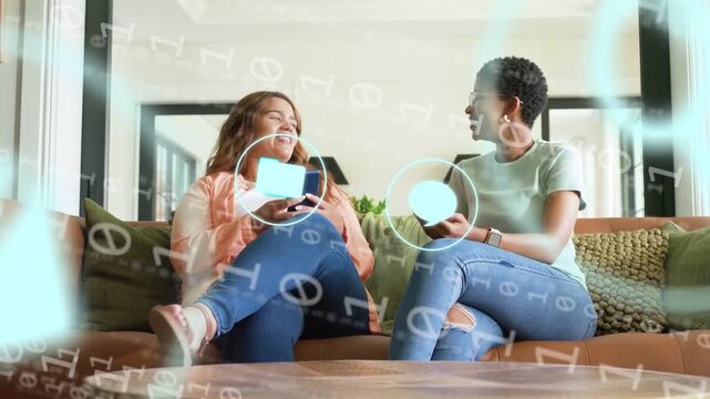 Two women showing phones sharing moment on sofa, sparking tech icons and binary moving then fading