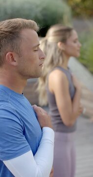 Vertical video: Diverse couple starting synchronized breathing on wooden deck near shrubs for calm