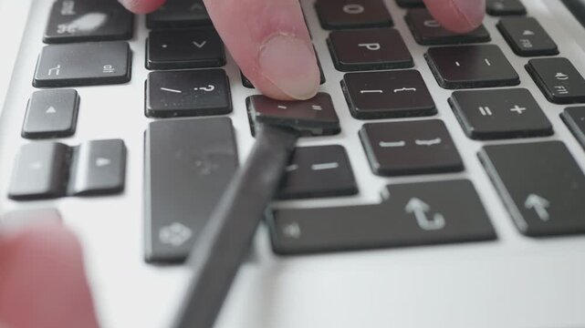 Close-up of person removing a laptop keyboard key for cleaning and repair.