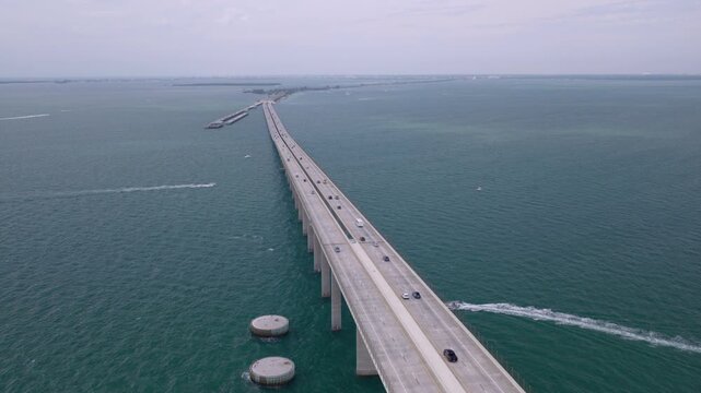 Aerial drone flyover of the Sunshine Skyway Bridge with traffic and boat wake in Tampa Bay Bridge