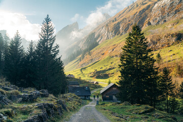 Obraz premium Switzerland fall mountain scenery with hikers on trail along traditional chalets, Seealpsee, Appenzell, Switzerland