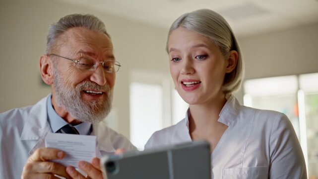 Two pharmacists working together holding tablet device pills in pharmacy closeup