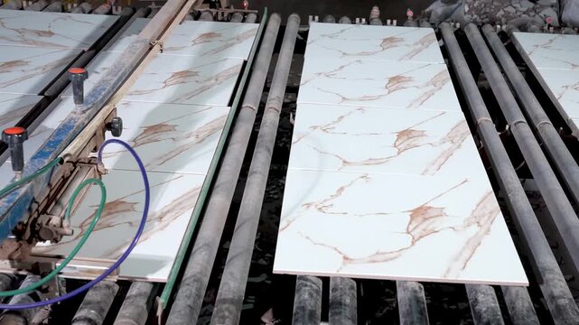 Printed ceramic tiles moving toward kiln on industrial conveyor in factory production line