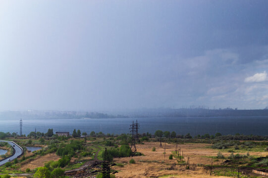Rainstorm over lake and industrial cityscape