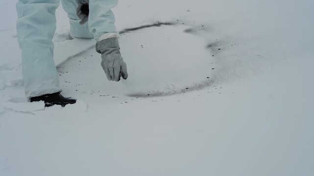 Gloved hands draw dark snow circle closeup forensic scene of researcher scraping black residue from rim, transferring granules into container, methodical motion and careful handling of evidence, cold