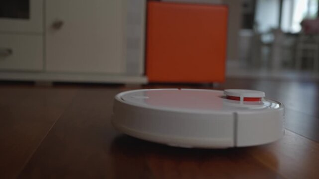 A robot vacuum cleaner efficiently navigates and cleans the parquet floor in the living room. The device maneuvers autonomously, providing a thorough cleaning of the surface.	
